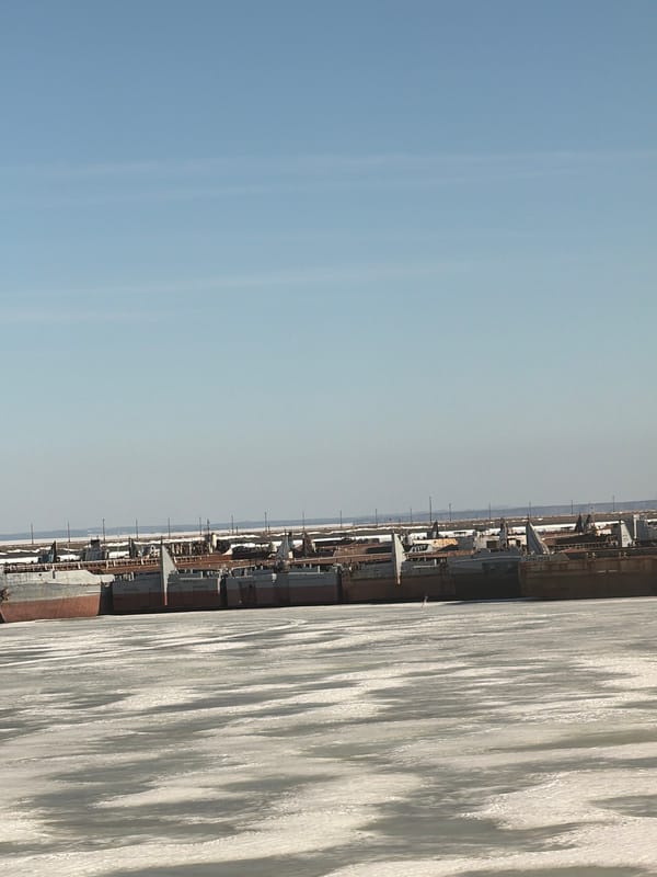 Ice-covered Kama River shows moored vessels, decaying ship hull