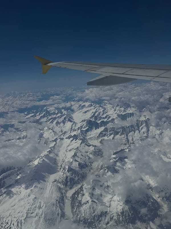 Aerial view captures aircraft wing over snowy mountains near London
