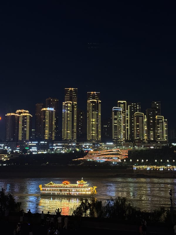 Illuminated boats cruise Chongqing's Jialing River amid glowing cityscape