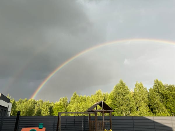 Rainbow breaks through stormy skies over a backyard