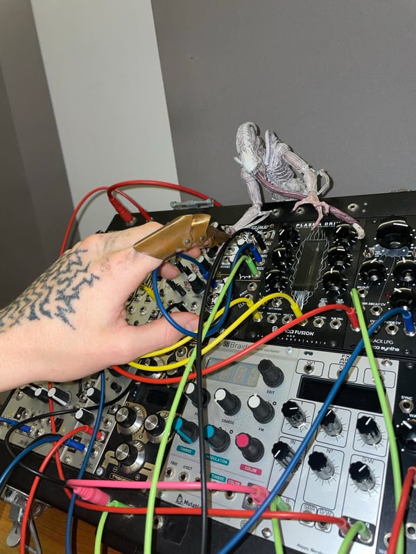 Person operates modular synthesizer with tattooed hand in Argentina