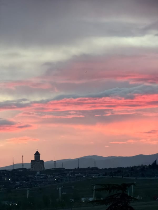 Sunset captures Tbilisi church silhouette against Georgian hills