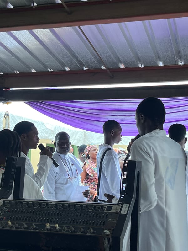 Outdoor religious gathering with live music and white-robed attendees