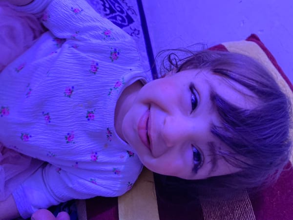 Child photographed indoors under purple lighting in Kandahar