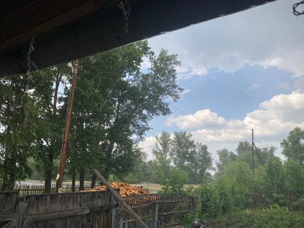 Rural Siberian village under a shifting, stormy summer sky