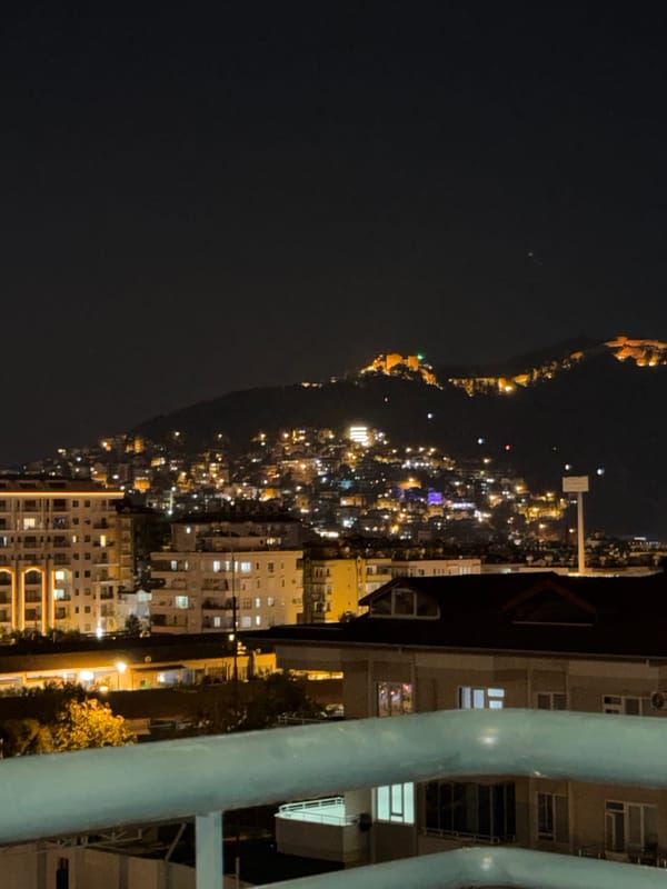 Balcony night with city views, poolside lights, and wine.