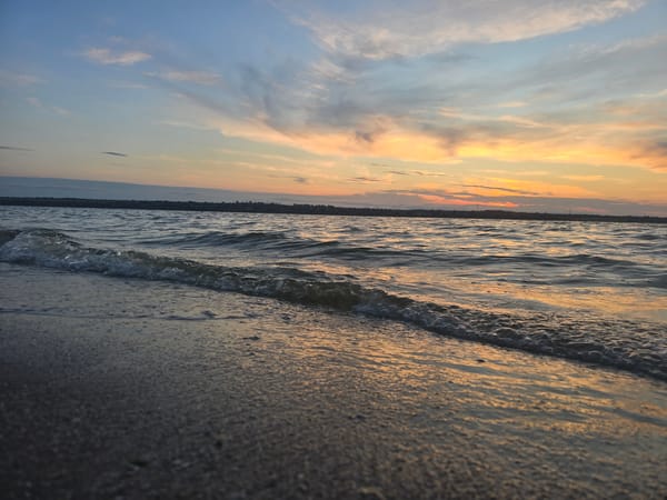 Sunset waves wash over reflective beach sand