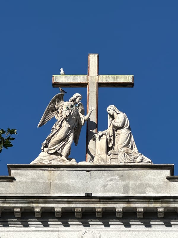 Weathered stone cross and angel sculpture on a Como rooftop