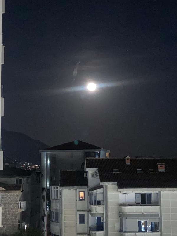 Bright moon illuminates nighttime urban scene in Budva, Montenegro