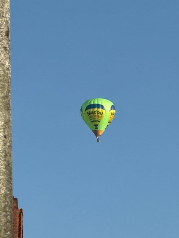 Hot air balloon, butterflies, and summer blooms over Bruges