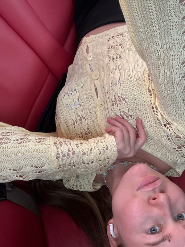 Overhead close-up of yellow lace cardigan on red leather seat