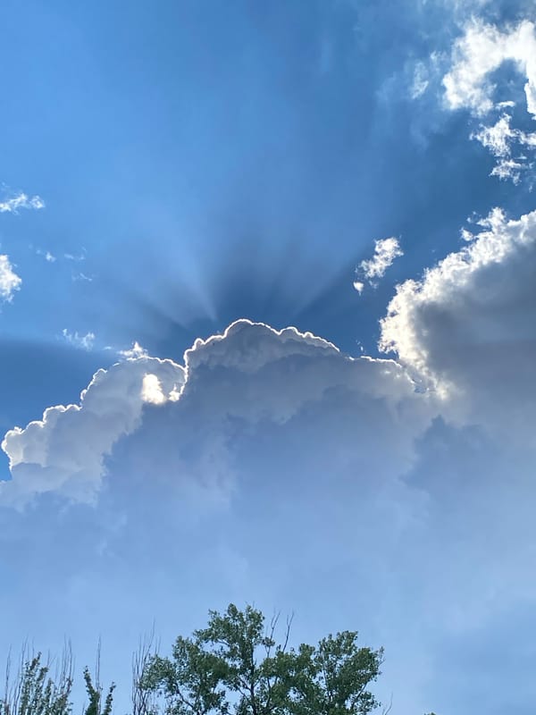 Dramatic sunbeams burst through clouds in afternoon sky