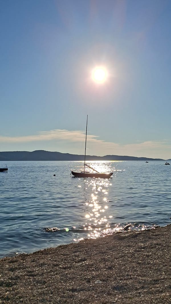 Bright sun reflects off calm coastal water on a clear day