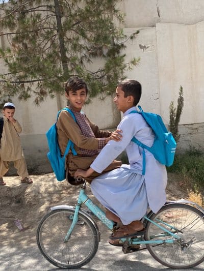 Boys share bicycle ride in Kandahar street scene
