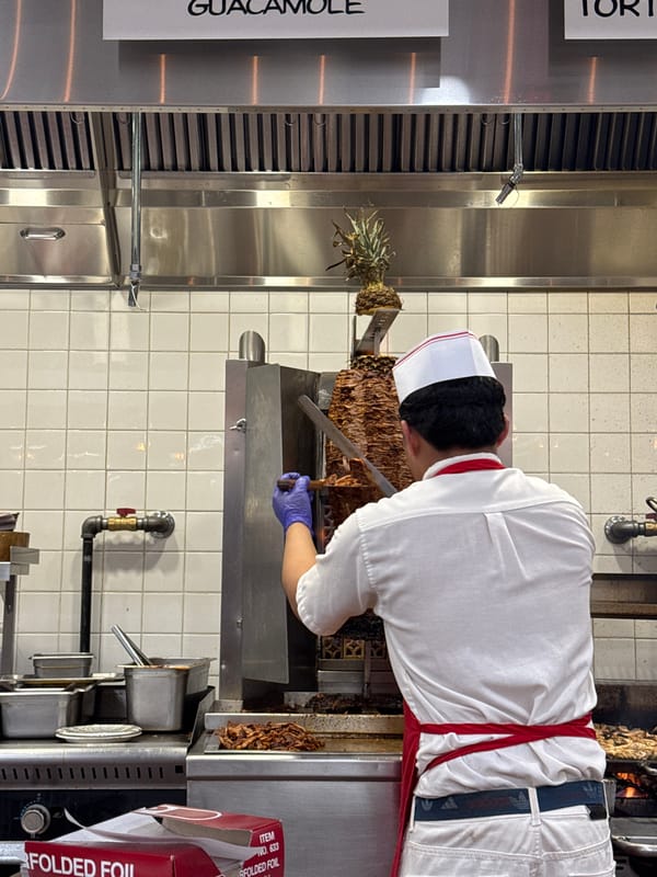 Kitchen worker slices meat from vertical spit in NYC