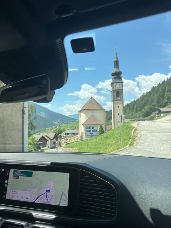 Alpine village and church steeple seen from a passing vehicle