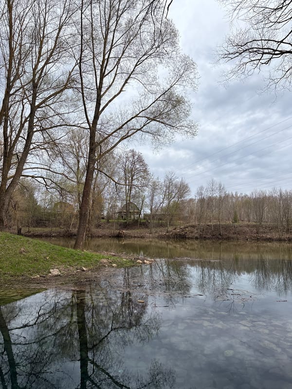 Woman visits waterfront in Russian village during spring afternoon