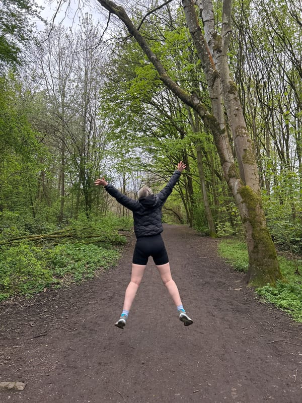 Person jumps playfully on Manchester woodland path