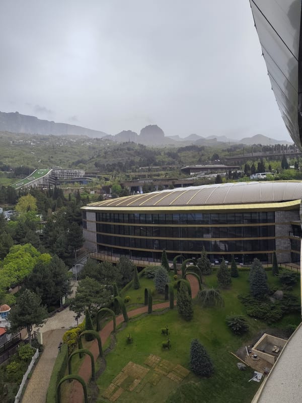 High-angle view captures modern complex amid mountains, cloudy skies