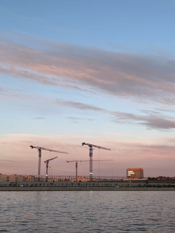 Dusk waterfront scene captured in Saint Petersburg with construction cranes