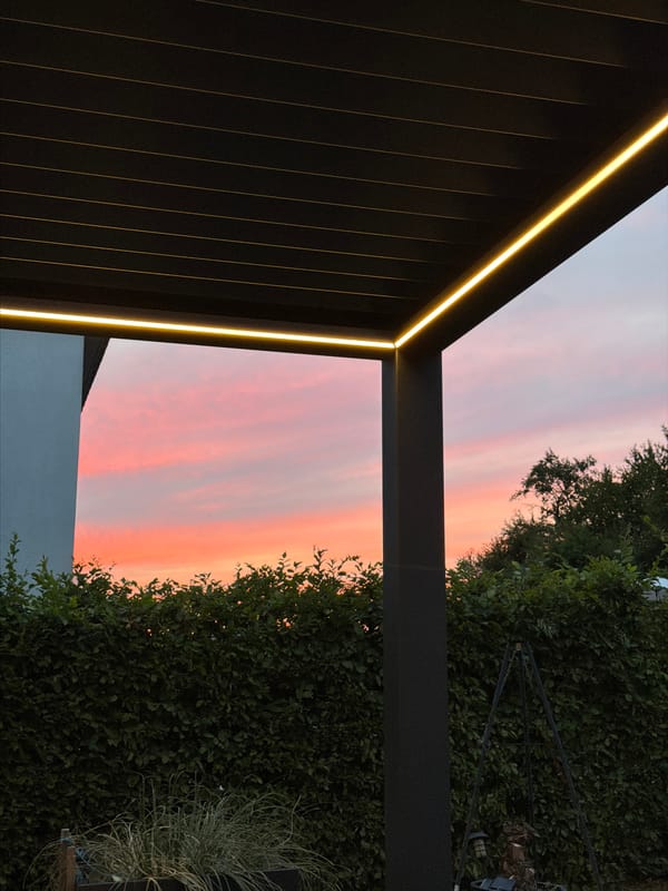 Backyard dinner under a pergola as dusk settles in Junglinster