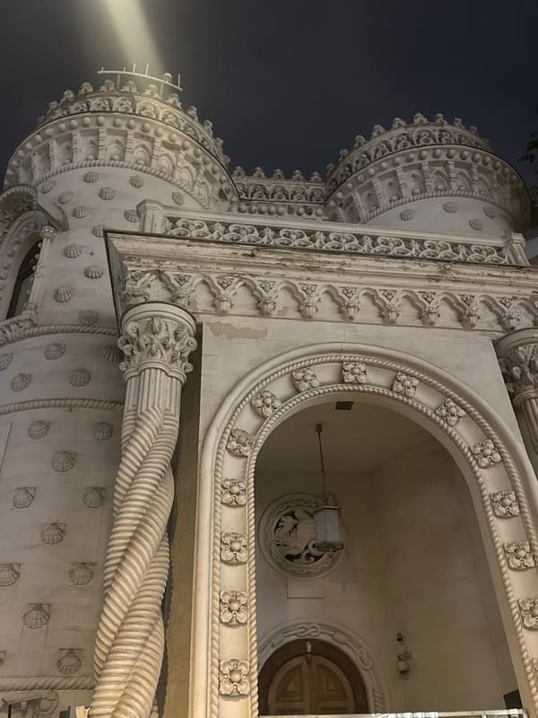 Ornate turreted building photographed at night, two angles