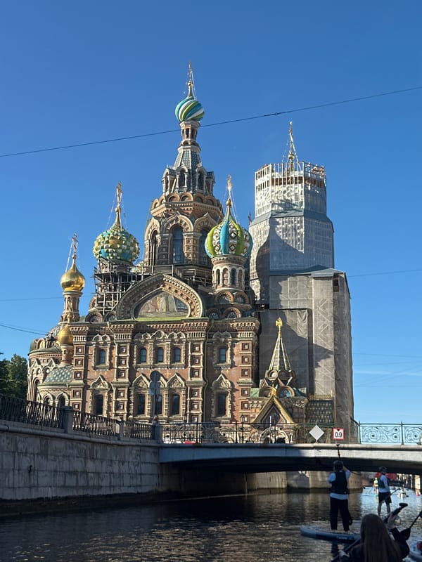 Paddleboarders pass a landmark church under renovation in St. Petersburg