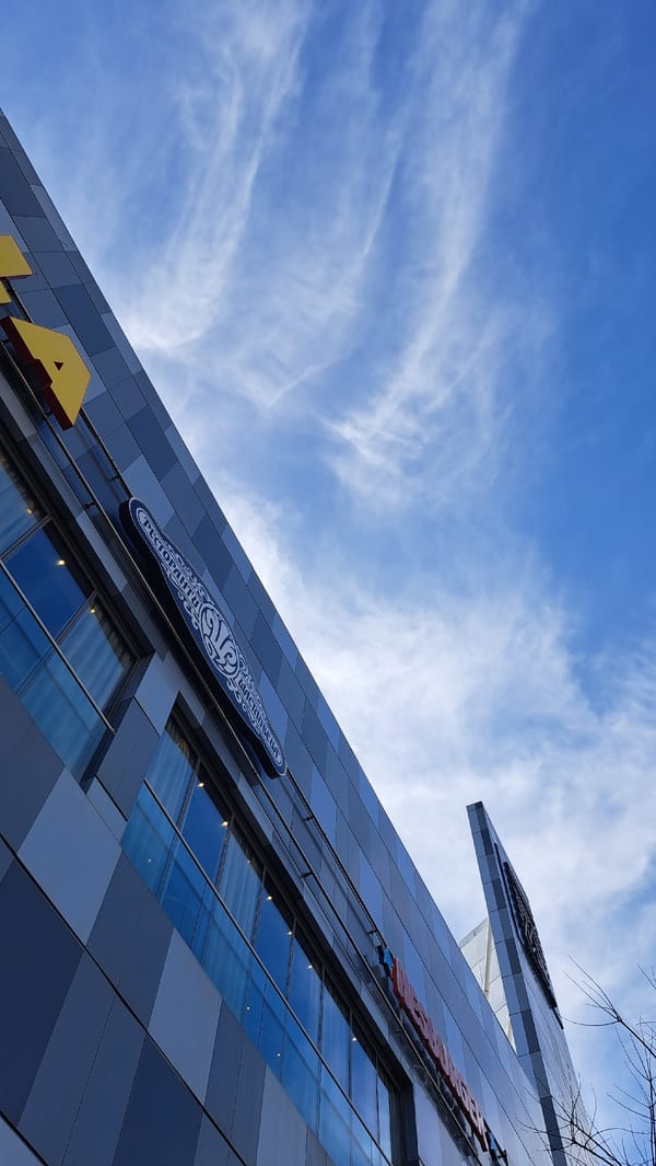 Modern grid-facade building photographed against blue sky with clouds