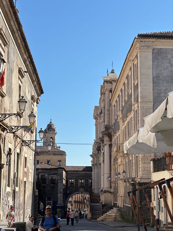 Colorful umbrella-decorated streets bustling with midday life in Catania