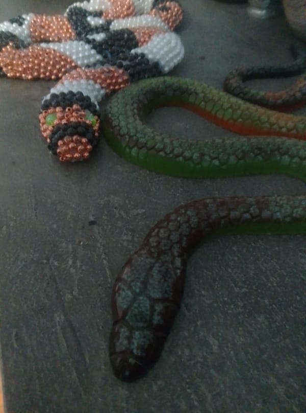 Beaded snake sculpture and small collectibles, close-up.