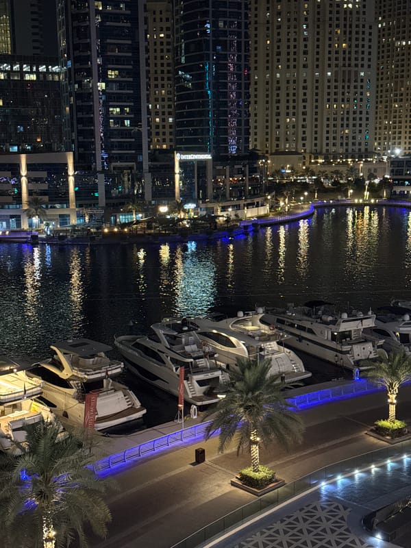 Dubai Marina skyline mirrors across the water at night.