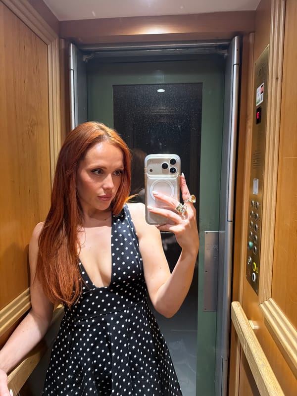 Woman takes selfies in Parisian elevator wearing polka-dot dress