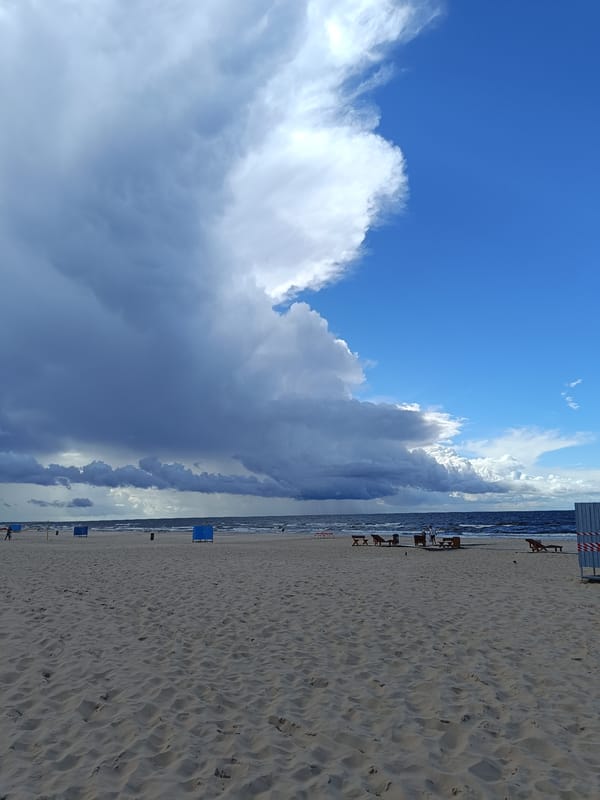 Kitesurfing and beachgoers on a stormy Baltic shore near Riga