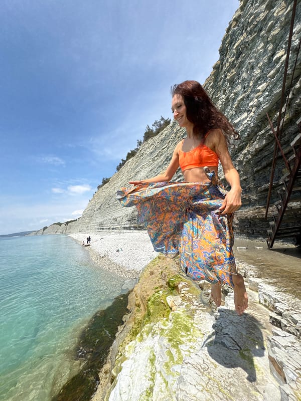 Woman poses for photo on sunny rocky beach