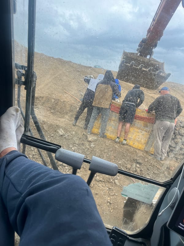 Four people rest on mat near construction site