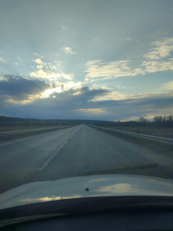 Vehicle travels rural highway under expansive sky in Niva, Russia