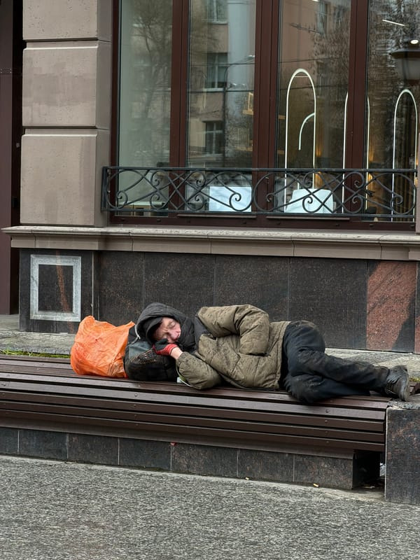 Man resting on urban bench with orange bag nearby