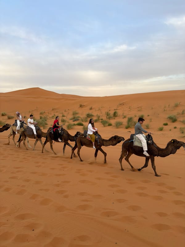 Camel riders traverse desert landscape near Rissani, Morocco