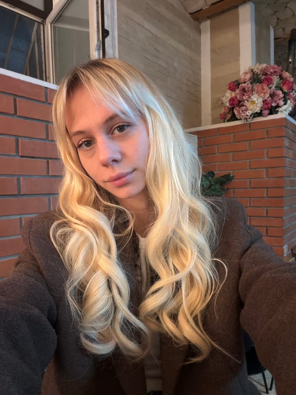 Woman poses with bouquet against brick backdrop in Moscow