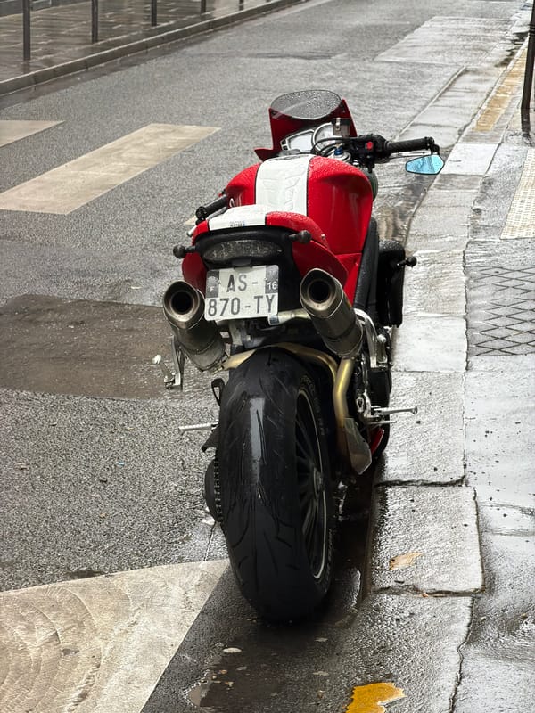 Motorcycle parked on wet Paris street during afternoon