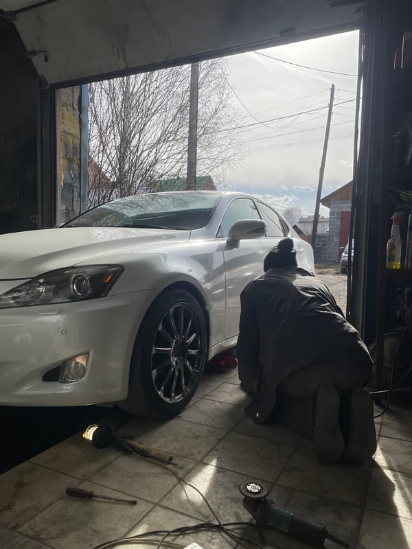Mechanic repairs white Lexus brakes in Russian garage