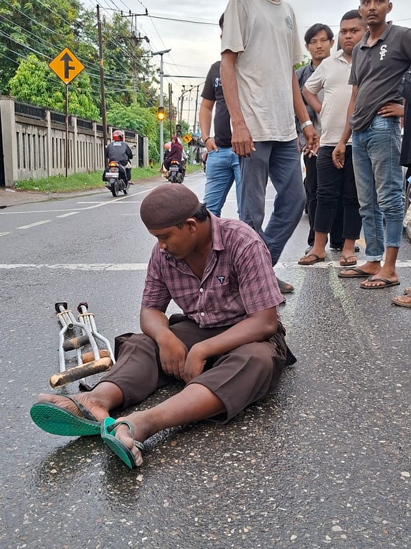 Man with crutches sits on street in Keudebayu