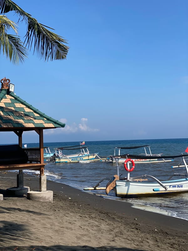 Black sand beach morning in Buleleng, boats and fruit