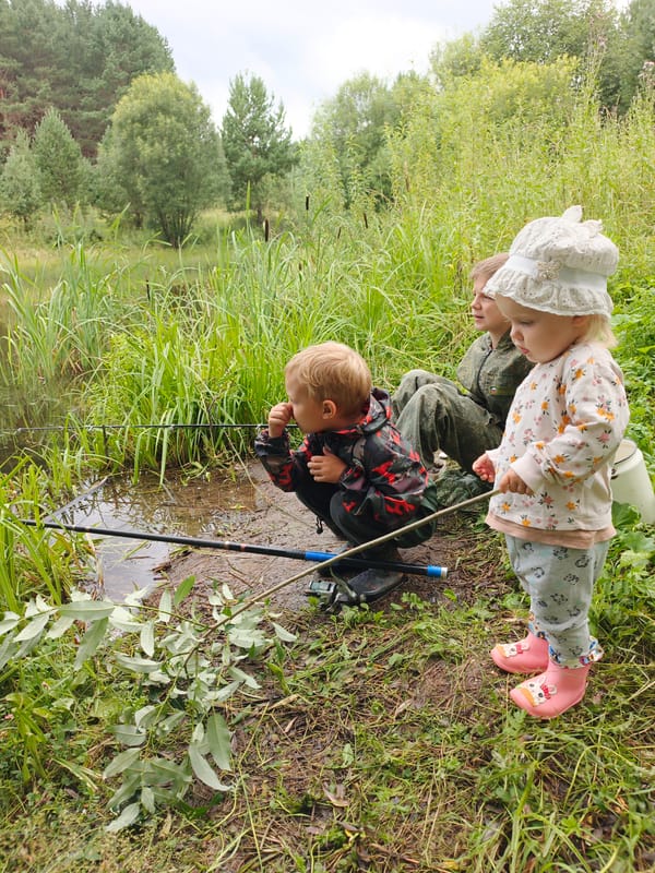 Kids fishing a rural Russian lake, wildflowers all around