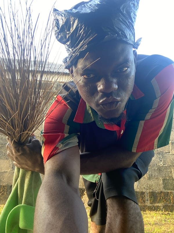Two people photographed outdoors in colorful clothing, one holding broom