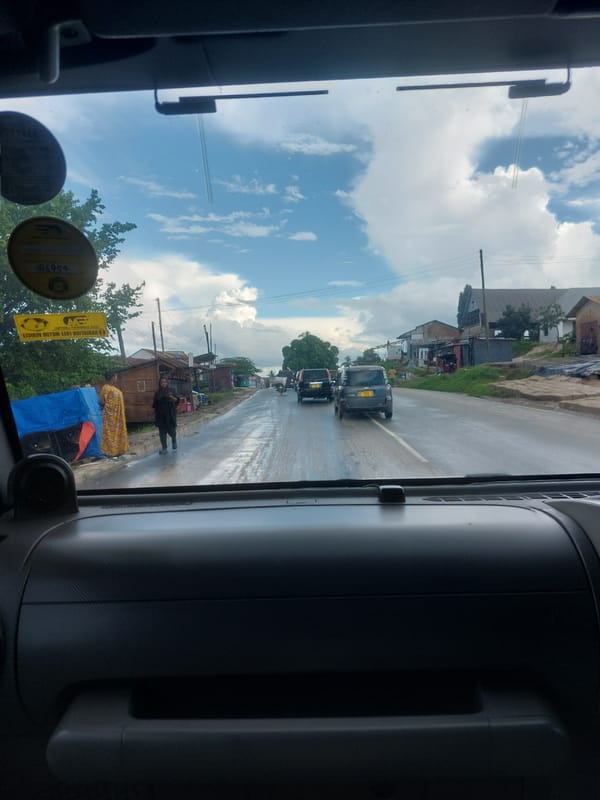 Traffic flows past person with blue tarp in Dar es-Salaam