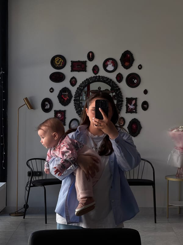 Woman documents ornate wall gallery with baby in Bataysk home