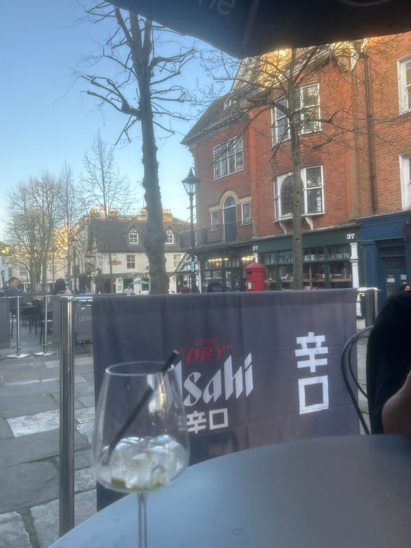Two women dine at outdoor cafe with Asahi signage