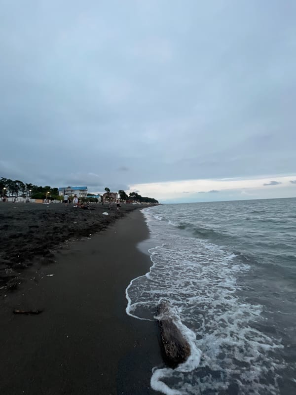 Overcast afternoon on Ureki's black sand beach and promenade