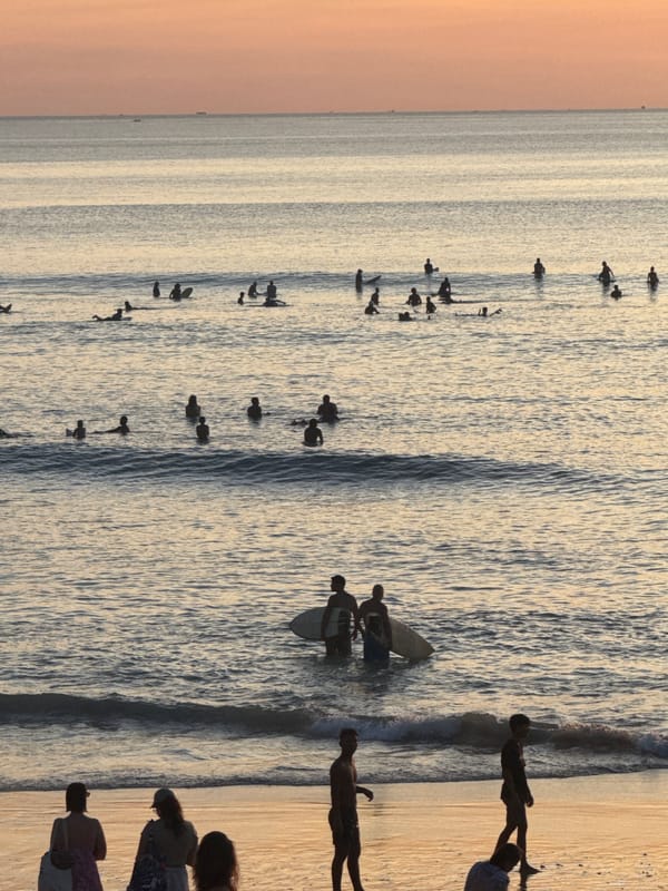 Surfers and beachgoers enjoy morning at Kuta Selatan beach